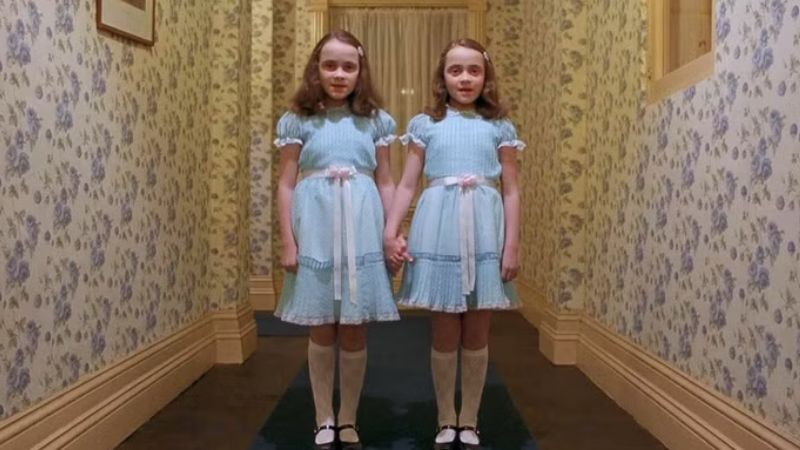 Gêmeas Grady no corredor do hotel em O Iluminado, clássico do terror psicológico. Foto: Reprodução.